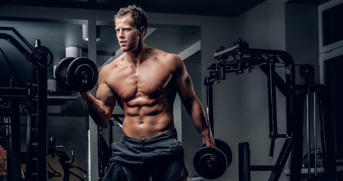 Premium Photo  Young athletic man pumping up muscles in the gym